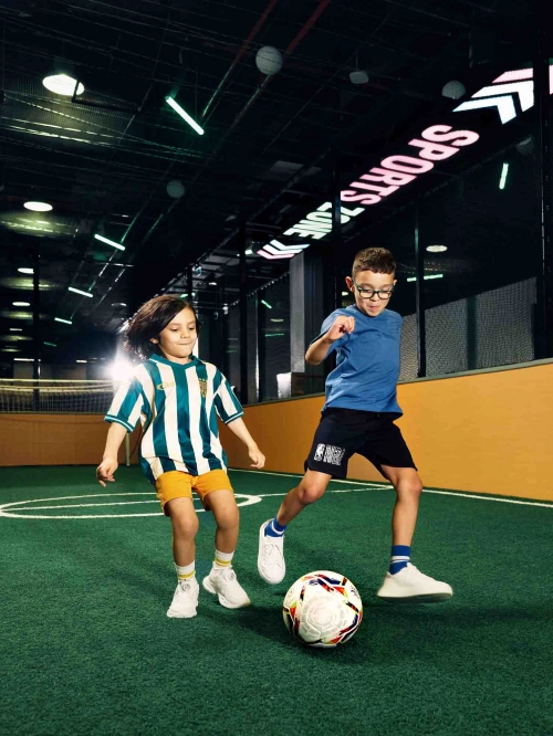 2 young boys playing football on the court